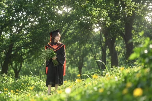碩士黑袍與橘色披肩，森林黃花草地 AI 生成示意照